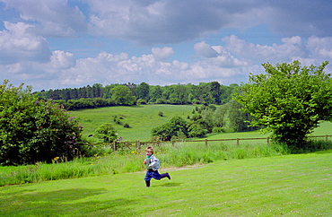 A four year old boy running across a field in Wiltshire, England