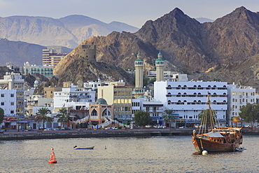 Mutrah Corniche and entrance to Mutrah Souq, backed by mountains, viewed from the sea, Muscat, Oman, Middle East