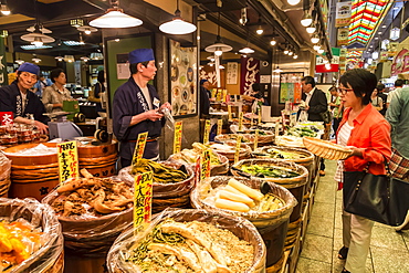 Shopper with basket considers purchase at local Japanese food stall, Nishiki Market (Kyoto's Kitchen), Downtown Kyoto, Japan, Asia