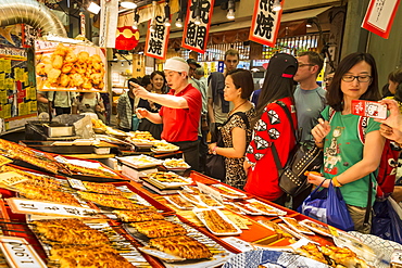 Customers queue at busy local Japanese teriyaki food stall, Nishiki Market (Kyoto's Kitchen), Downtown Kyoto, Japan, Asia