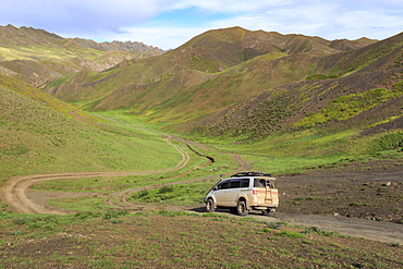 Vehicle travels off road through lush mountains, Gurvan Saikhan National Park, near Yolyn Am (Yol Valley), Gobi Desert, Mongolia, Central Asia, Asia