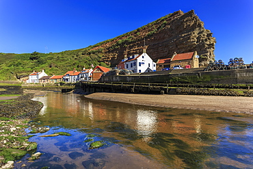 Harbour cottages beneath steep cliffs, fishing village, low tide in summer, Staithes, North Yorkshire Moors National Park, Yorkshire, England, United Kingdom, Europe