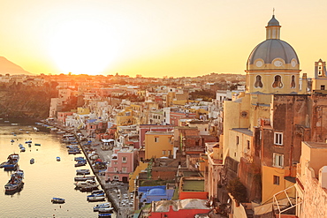 Marina Corricella at sunset, fishing village, colourful fishermen's houses, boats and church, Procida Island, Bay of Naples, Campania, Italy, Europe