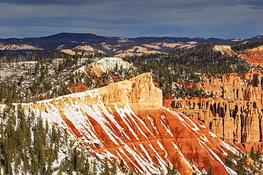 Snowy cliffs, pine trees and hoodoos lit by morning sun with cloudy sky, Rainbow Point, Bryce Canyon National Park, Utah, United States of America, North America