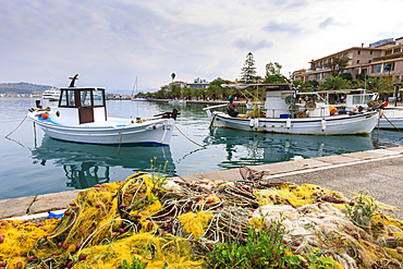 Colourful fishing nets on quay, boats, man mending nets, waterfront, Nafplio (Nafplion), Argolic Gulf, Peloponnese, Greece, Europe