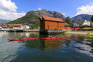 Sea kayakers head off, beautiful Eidfjord village, mountains and beach, sunny day, Norwegian Western Fjords, Norway, Scandinavia, Europe