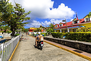 Couple on moped, colourful Bourg des Saintes town, Terre de Haut, Iles Des Saintes, Les Saintes, Guadeloupe, Leeward Islands, West Indies, Caribbean, Central America