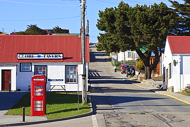 Red telephone box in Crozier Place with view up steep Philomel Street, Stanley, Port Stanley, East Falkland, Falkland Islands, South America