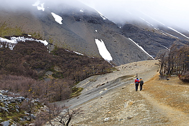 Hikers walking on a trail from the base of the Paine towers, Torres del Paine, Patagonia, Chile, South America 