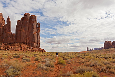 Navajo person rides a horse between rock formations, Monument Valley Navajo Tribal Park, Utah Arizona, United States of America