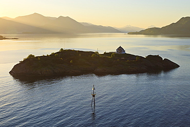 Islet with house lit by shafts of sunlight at dawn, entrance to Romsdalsfjord, Norway, Scandinavia, Europe 