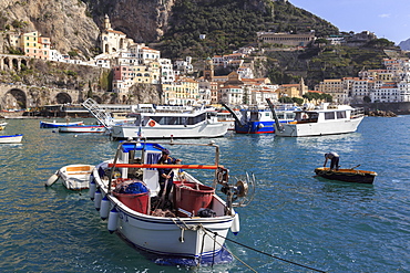 Fisherman in fishing boat in Amalfi harbour, from quayside with view towards Amalfi town, Costiera Amalfitana (Amalfi Coast), UNESCO World Heritage Site, Campania, Italy, Europe