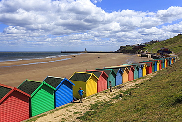 Children kick football near colourful beach huts above West Cliff Beach, Whitby, North Yorkshire, England, United Kingdom, Europe