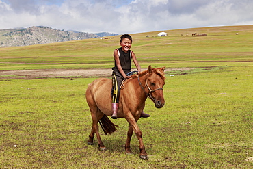 Horse and smiling boy riding bareback with ger and hills behind at summer nomad camp, Khujirt, Uvurkhangai (Ovorkhangai), Central Mongolia, Central Asia, Asia