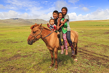 Four nomad siblings on their tame horse at summer nomad camp, Khujirt, Uvurkhangai, Central Mongolia, Central Asia, Asia