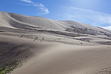 Distant people descending a huge sand dune, iridescent on a summer evening, Khongoryn Els, Gobi Desert, Mongolia, Central Asia, Asia