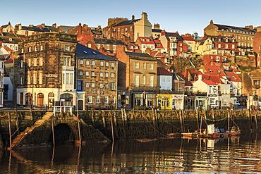 Townhouses, bars and restaurants on Pier Road, West Side of River Esk, lit by low sun in winter, Whitby, North Yorkshire, England, United Kingdom, Europe