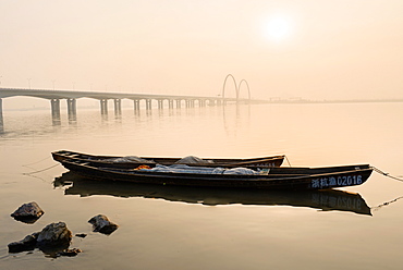 Fishing boats and modern bridge in mist at Qiantangjiang River in Hangzhou, Zhejiang, China, Asia 