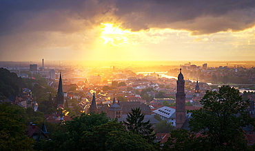 Golden afternoon sun dramatically breaking through rain clouds over the spires of Heidelberg Old Town, Baden-Wurttemberg, Germany, Europe