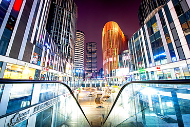 Escalator railings and illuminated futuristic architecture at Sanlitun SOHO, Beijing, China, Asia