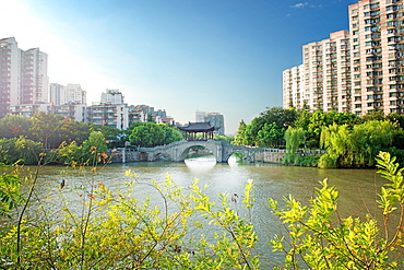 Stone bridge with pagoda style roofing, flanked by old style apartment buildings on the left and newer ones on the right, Hangzhou, China, Asia