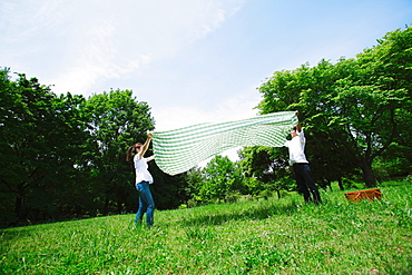 Couple Spreading Picnic Cloth in Park