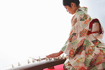 Japanese woman in a kimono playing the koto