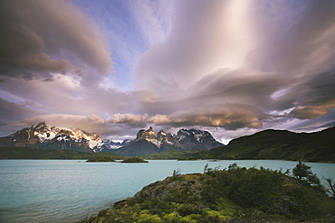 Cloud formations in the skies above the Torres del Paine National Park in Chile. Sunset over the waters of the sea, and snowcapped peaks, Torres del Paine national park, Chile