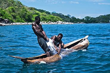 Fishermen pulling in nets in a dugout canoe on Lake Malawi (East Africa)