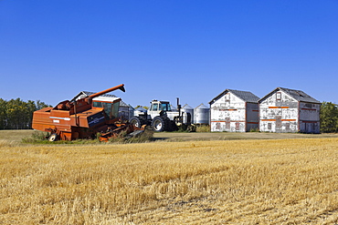 View of harvester in landscape with garnary on Highway 6, Saskatchewan, Canada