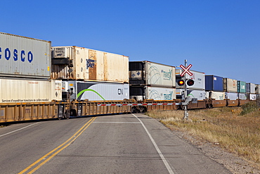 View of cargo train crossing railroad on Highway 15, Saskatchewan, Canada