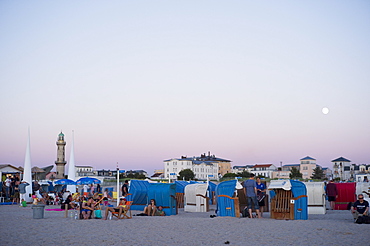 Evening beach life â€“ sunset with a full moon on the sandy beach at WarnemÃ¼nde, Rostock