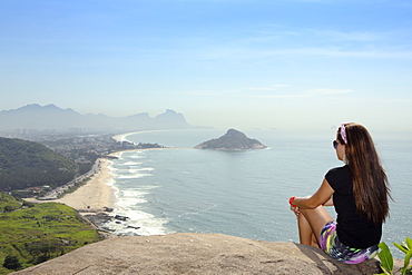 A young hiker looking out from the viewpoint over Pontal and Recreio dos Bandeirantes beaches in Barra da Tijuca, Rio de Janeiro, Brazil, South America