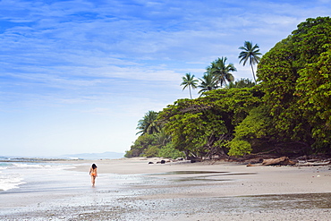 A young woman walking along Manzanillo beach in Santa Teresa, Nicoya peninsula, Puntarenas, Costa Rica, Central America