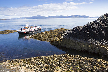 Basalt columns and a tourist ferry, Staffa Island, Inner Hebrides, Scotland, United Kingdom, Euorpe