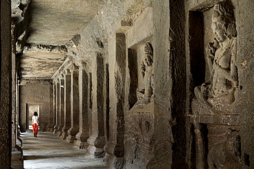 A woman walking through a corridor in the Hindu temple in the Kailash (Kailaszanatha) cave temple in Ellora, UNESCO World Heritage Site, Maharashtra, India, Asia