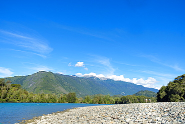 Fishermen walking along a shingle beach next to the trout-filled Puelo River in Northern Patagonia, Chile, South America