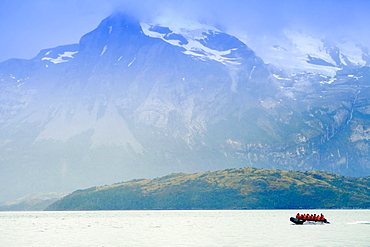 Dingy in a fjord in Alberto de Agostini National Park with the Darwin mountain range (Cordillera Darwin) behind, Patagonia, Chile, South America