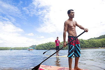 Locals riding stand-up surf boards, Caraiva River. Bahia, Brazil, South America