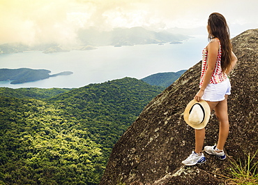 Young woman looking out over the Green Coast (Costa Verde) from Papapagaio peak (Pico do Papagaio) on Ilha Grande island, Rio de Janeiro state, Brazil, South America