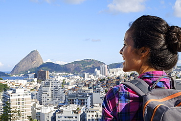 Young backpacker on her mobile phone in central Rio de Janeiro with the Sugar Loaf in the distance, Rio de Janeiro, Brazil, South America