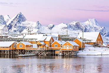 The colors of dawn frame the fishermen's houses surrounded by frozen sea, Sakrisoy, Reine, Nordland, Lofoten Islands, Arctic, Norway, Scandinavia, Europe