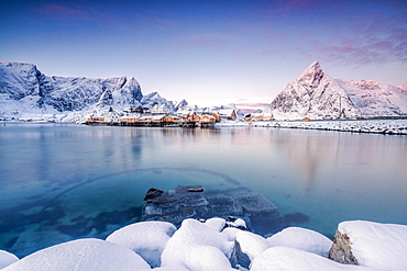 The colors of dawn frame the fishermen's houses surrounded by frozen sea, Sakrisoy, Reine, Nordland, Lofoten Islands, Arctic, Norway, Scandinavia, Europe