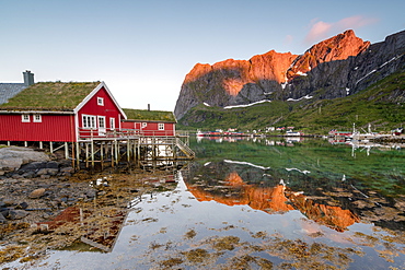 Fishing village and peaks reflected in water under midnight sun, Reine, Nordland county, Lofoten Islands, Arctic, Northern Norway, Scandinavia, Europe