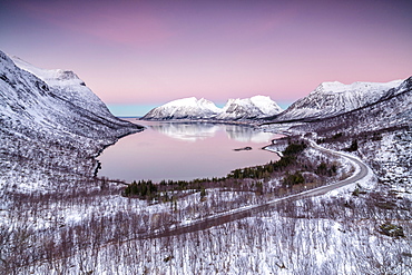 Pink sky at sunrise lights up the snowy peaks reflected in the cold sea, Bergsbotn, Senja,Troms County, Norway, Scandinavia, Europe