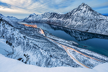 The snowy peaks above the frozen sea framed by the blue lights of dusk, Gryllefjorden, Senja, Troms County, Arctic, Norway, Scandinavia, Europe