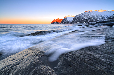 The waves of the icy sea crashing on the rocky cliffs at dawn Tungeneset, Senja, Troms county, Arctic, Norway, Scandinavia, Europe