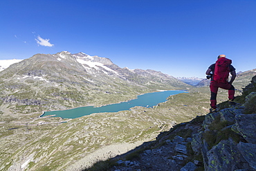 Hiker admires the blue alpine lake from Pizzo Campaccio, Bernina Pass, Canton of Graubunden, Engadine, Swiss Alps, Switzerland, Europe