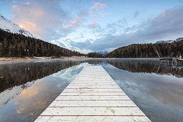 The wooden deck frames Lej Da Staz at dawn, St. Moritz, Canton of Graubunden, Engadine, Switzerland, Europe