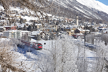 The red train runs across the snowy landscape around Samedan, Maloja, Canton of Graubunden, Engadine, Switzerland, Europe